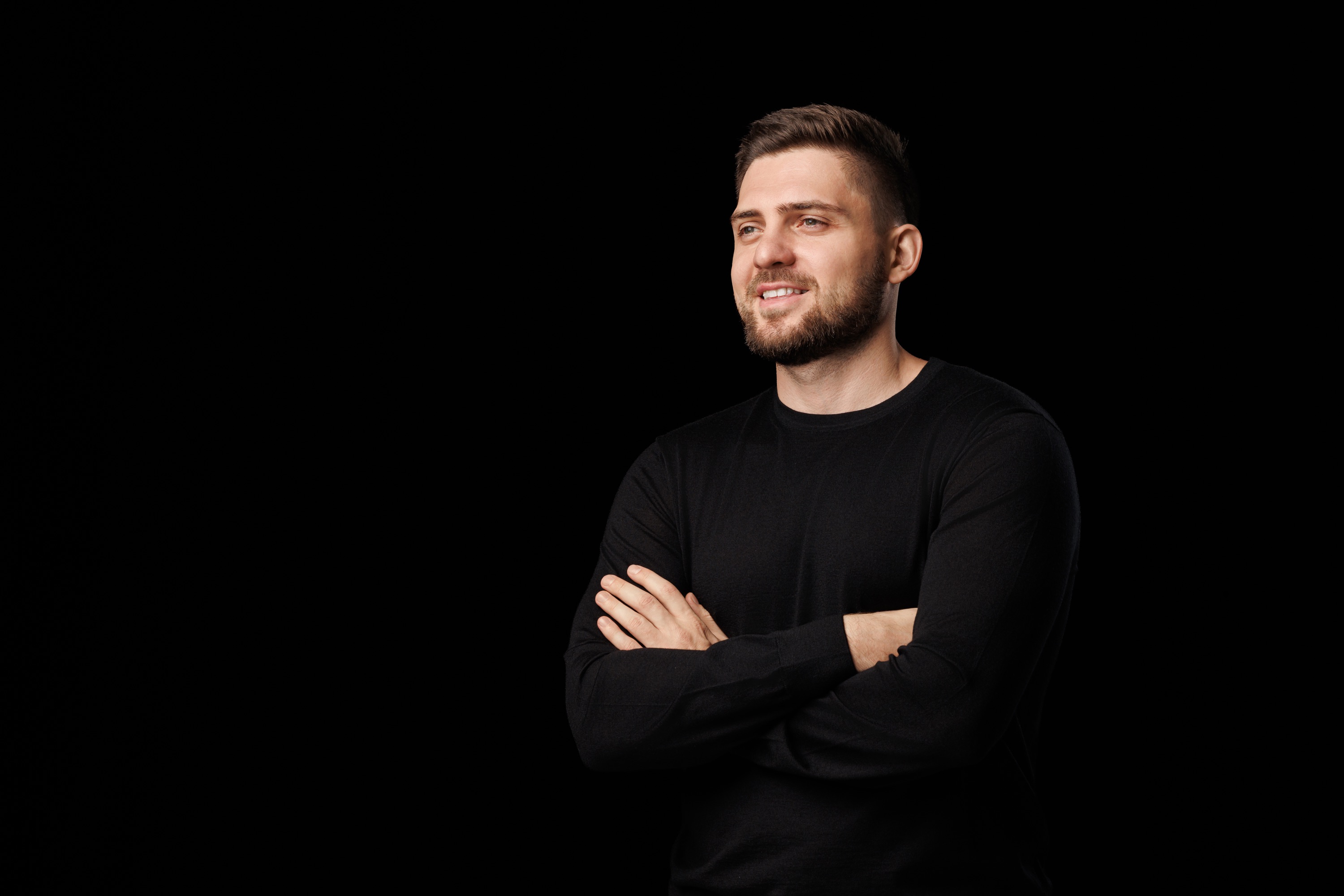 Pavlo Kharmanskyi — portrait, smiling, black sweater against a dark wall